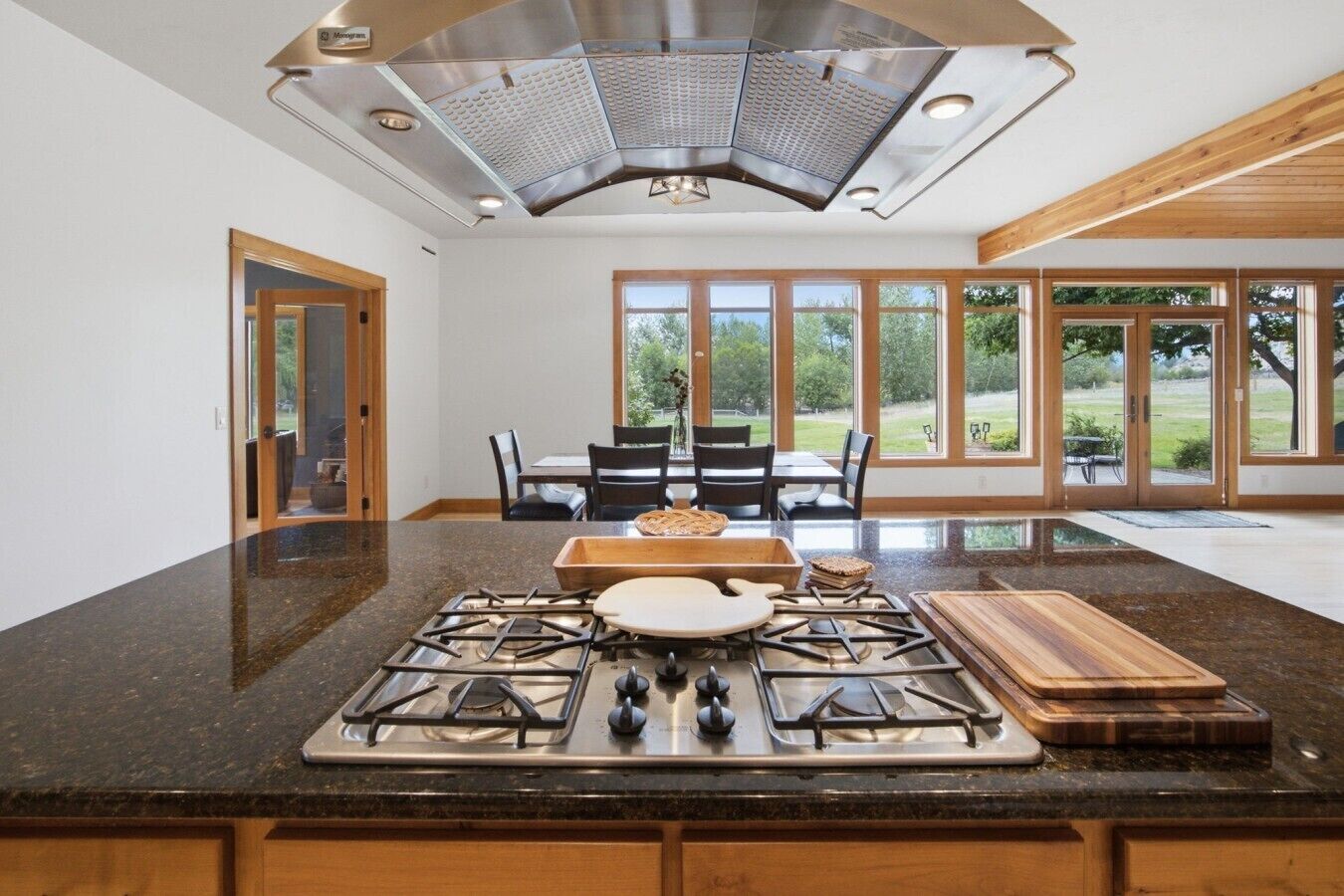 A kitchen with a central island, a gas stove, and a large window overlooking a garden.