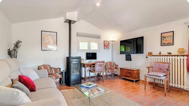 Ein Wohnzimmer mit einer Couch, Sesseln, einem Couchtisch, einem Fernseher und einem Kamin.