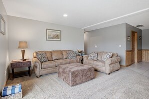 A living room with a beige sofa set, a matching ottoman, a side table with a lamp, and a framed picture on the wall. - Private Hot Tub with Perfect Mountain Views (Stevensville)