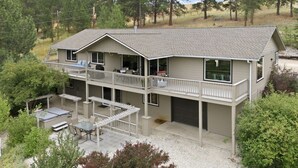 A two-story building with a balcony, outdoor seating area, and a garage. - Private Hot Tub with Perfect Mountain Views (Stevensville)