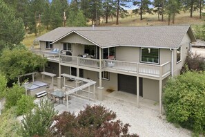 A two-story building with a balcony, outdoor seating area, and a garage. - Private Hot Tub with Perfect Mountain Views (Stevensville)