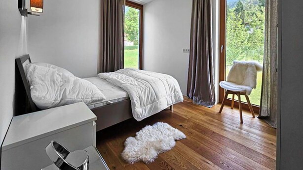 Une chambre à coucher avec un lit, une chaise, un bureau et une vue sur l’extérieur.