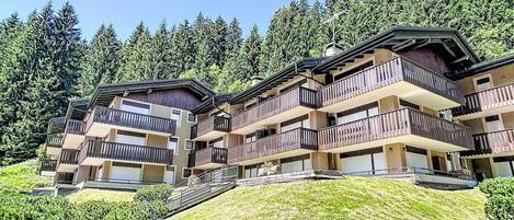 Un hotel de varios pisos con balcones, con árboles y un cielo despejado de fondo.