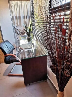 A modern room with a glass table, a black chair, and a decorative plant. - Red Studio/Apartment with Garden - Welcome Home (Windhoek)