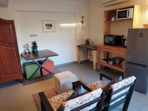 A compact living space with a kitchenette, a dining area with a table and chairs, and a seating area with a sofa. - Red Studio/Apartment with Garden - Welcome Home (Windhoek)