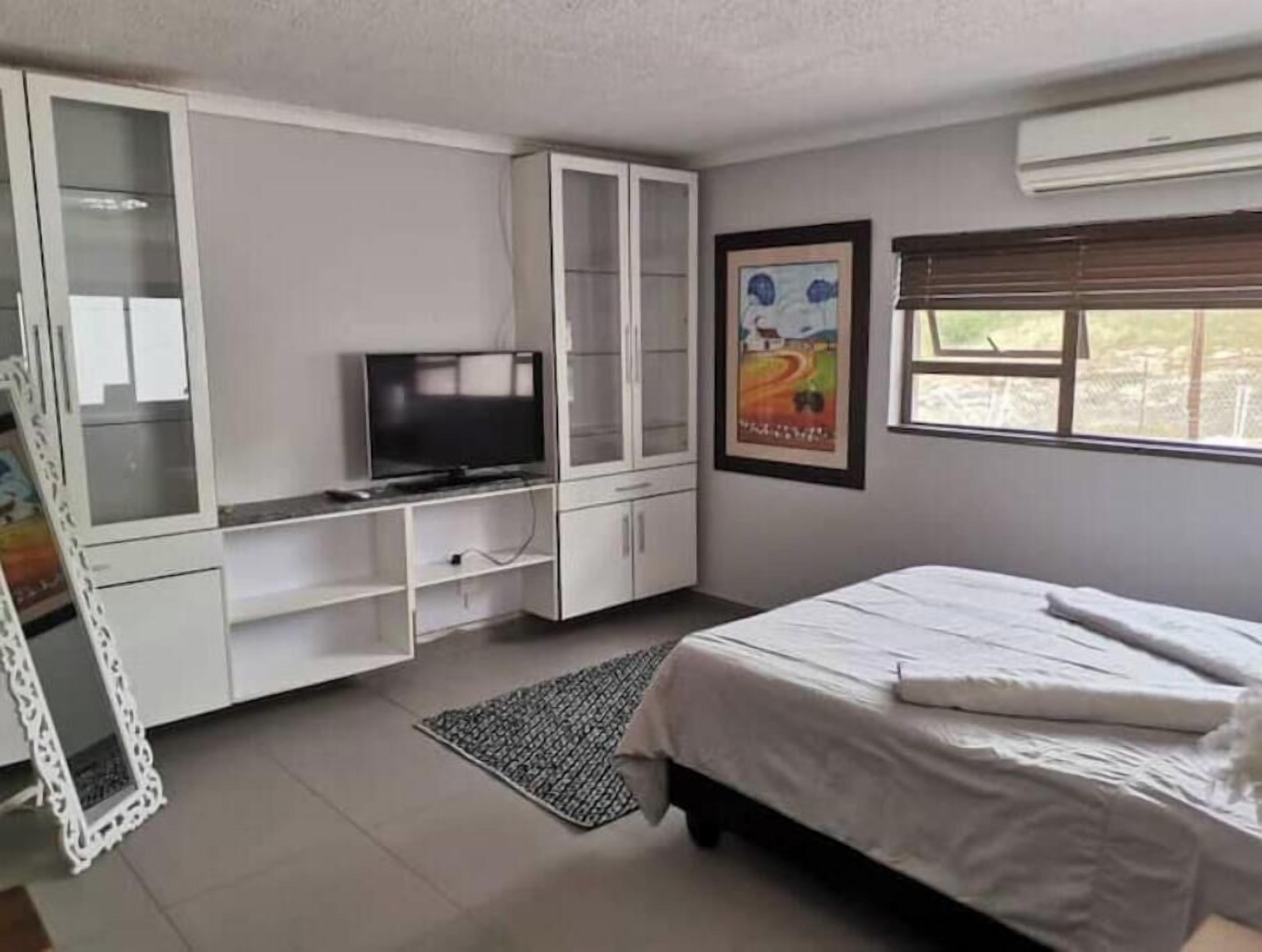 A bedroom with a bed, a television, a cabinet, and a window.