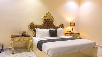 Un dormitorio con una cama grande, cabecera ornamentada, mesitas de noche y una lámpara.
