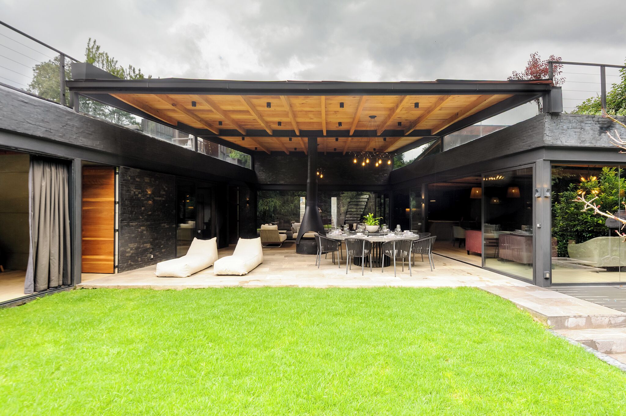 Une terrasse extérieure moderne, dotée d’un plafond en bois, d’une table à manger et de sièges.