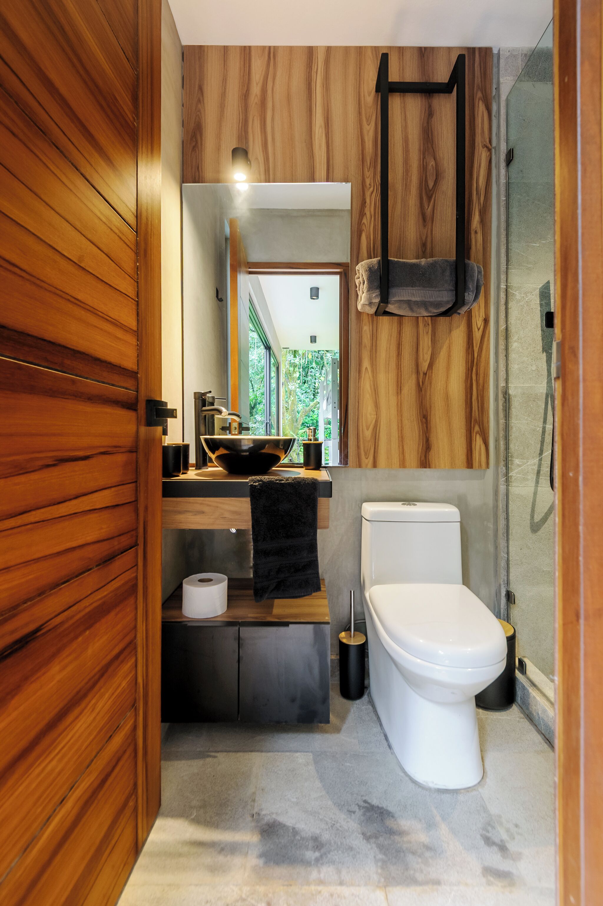 Un baño moderno con tocador de madera, inodoro blanco y cabina de ducha con mampara de cristal.