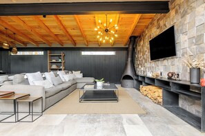 Una sala de estar moderna con un sofá modular, una mesa de centro, una chimenea y un televisor montado en una pared de piedra.