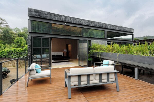 A modern outdoor deck with a sofa and chairs, a fireplace, and a view of the surrounding landscape. - Rancho Olivos Mountain House w Hot Tub (Valle de Bravo)