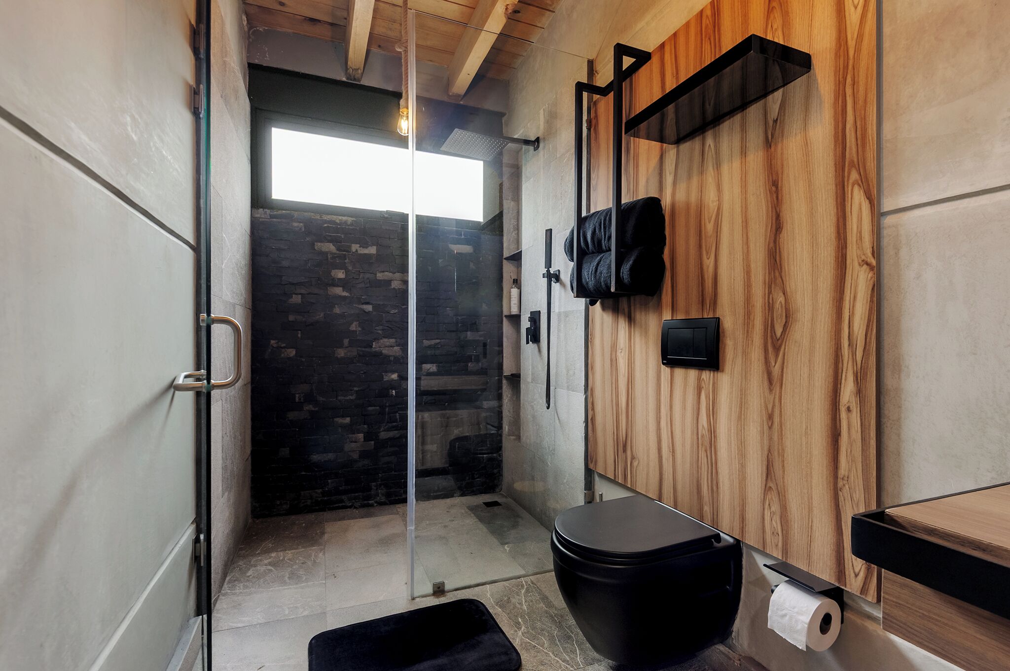 A bathroom with a shower, toilet, and a wooden wall.