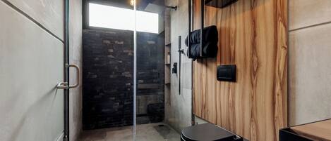 A bathroom with a shower, toilet, and a wooden wall.