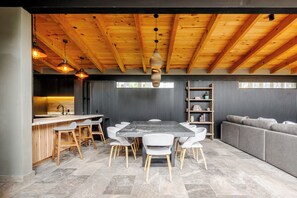 Una cocina moderna con comedor, vigas de madera en el techo y un sofá gris.