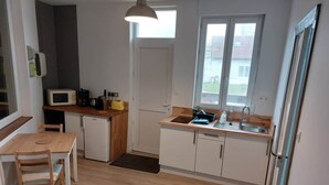 Cocina compacta con microondas, pileta y mesa de comedor de madera.
