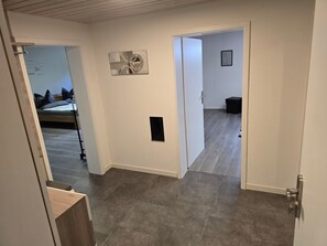A hallway with a bed, a door, and a small black object on the wall. - Apartment "Gabi" – Comfortable Stay in Hahnbach for up to 3 Guests (Hahnbach)