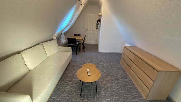 A narrow hallway with a sofa, a small table, and a wooden bench. - Ostfriesenfischer (Leezdorf)