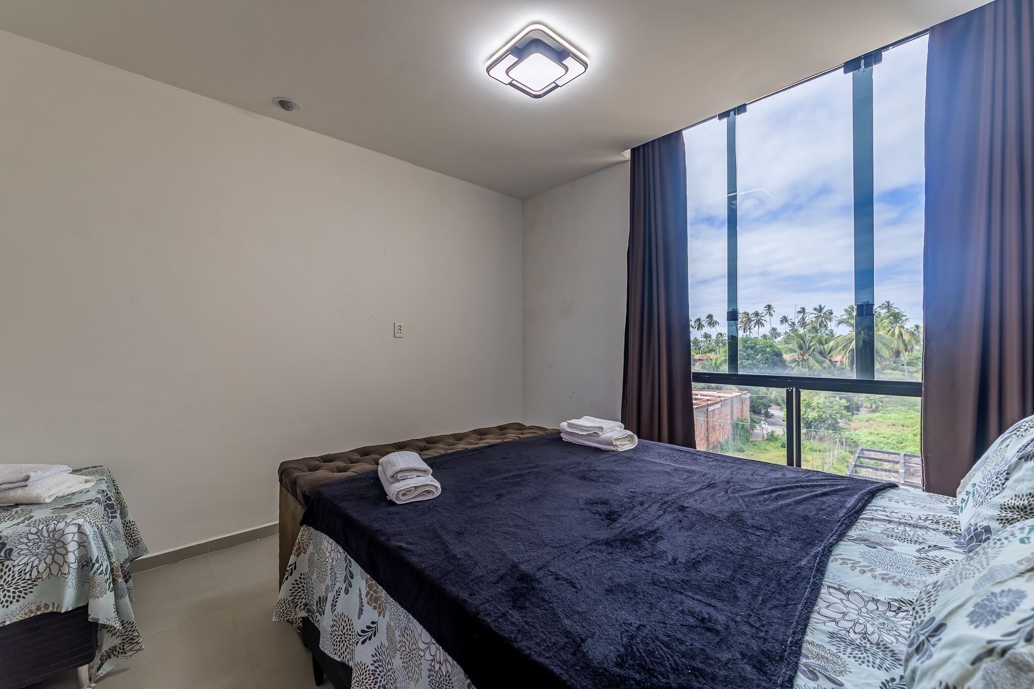 Una camera da letto con un letto, una finestra con tende e vista su un paesaggio verde.