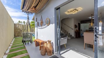 Um espaço ao ar livre moderno, com um banco de madeira, cestos de vime e um painel decorativo.