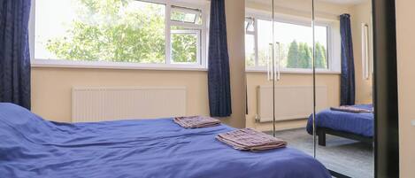 Una habitación con una cama grande, una cama más pequeña, una ventana y un espejo.
