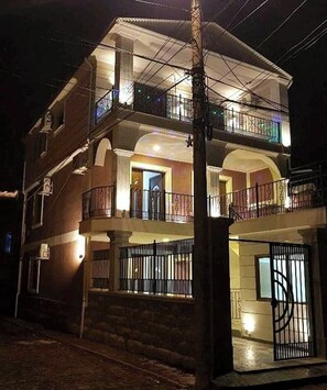 Un edificio residencial de varios pisos con balcones, un patio central y una entrada con portón.
