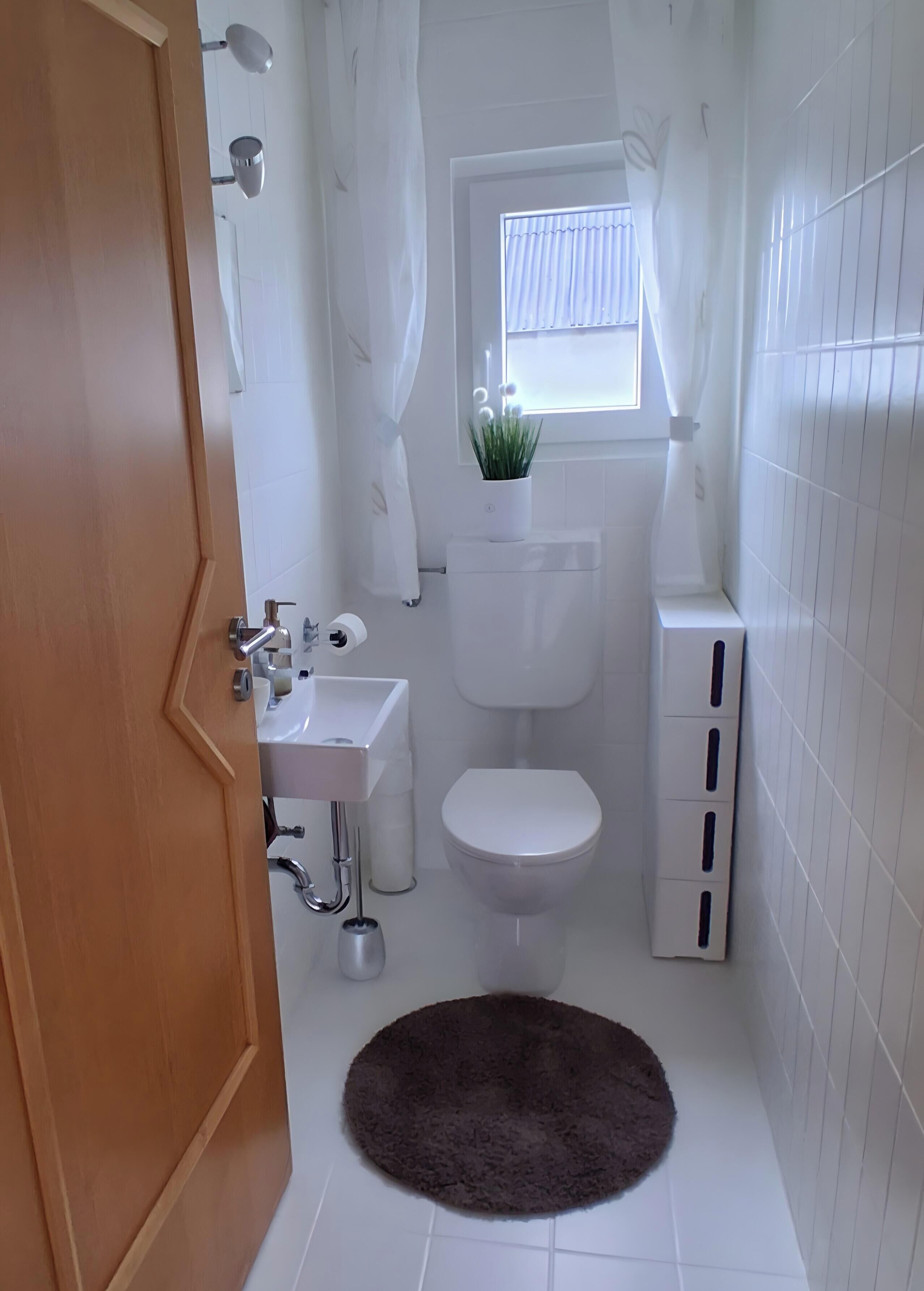 Un bagno con il water, un lavandino e una finestra con tende.