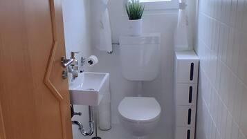 Un bagno con il water, un lavandino e una finestra con tende.
