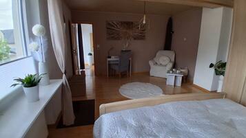 Een slaapkamer met een bed, een bureau, een stoel en een raam met gordijnen.