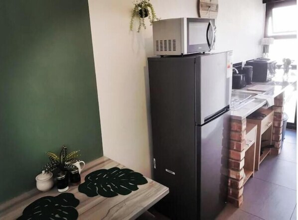 Eine Küche mit Kühlschrank, Mikrowelle und einer Arbeitsplatte mit verschiedenen Gegenständen.