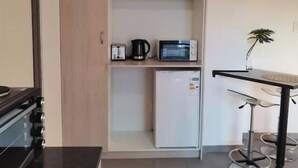 A compact kitchenette with a microwave, coffee maker, and refrigerator.