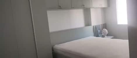 Un dormitorio con cama, mesita de noche y ventana.
