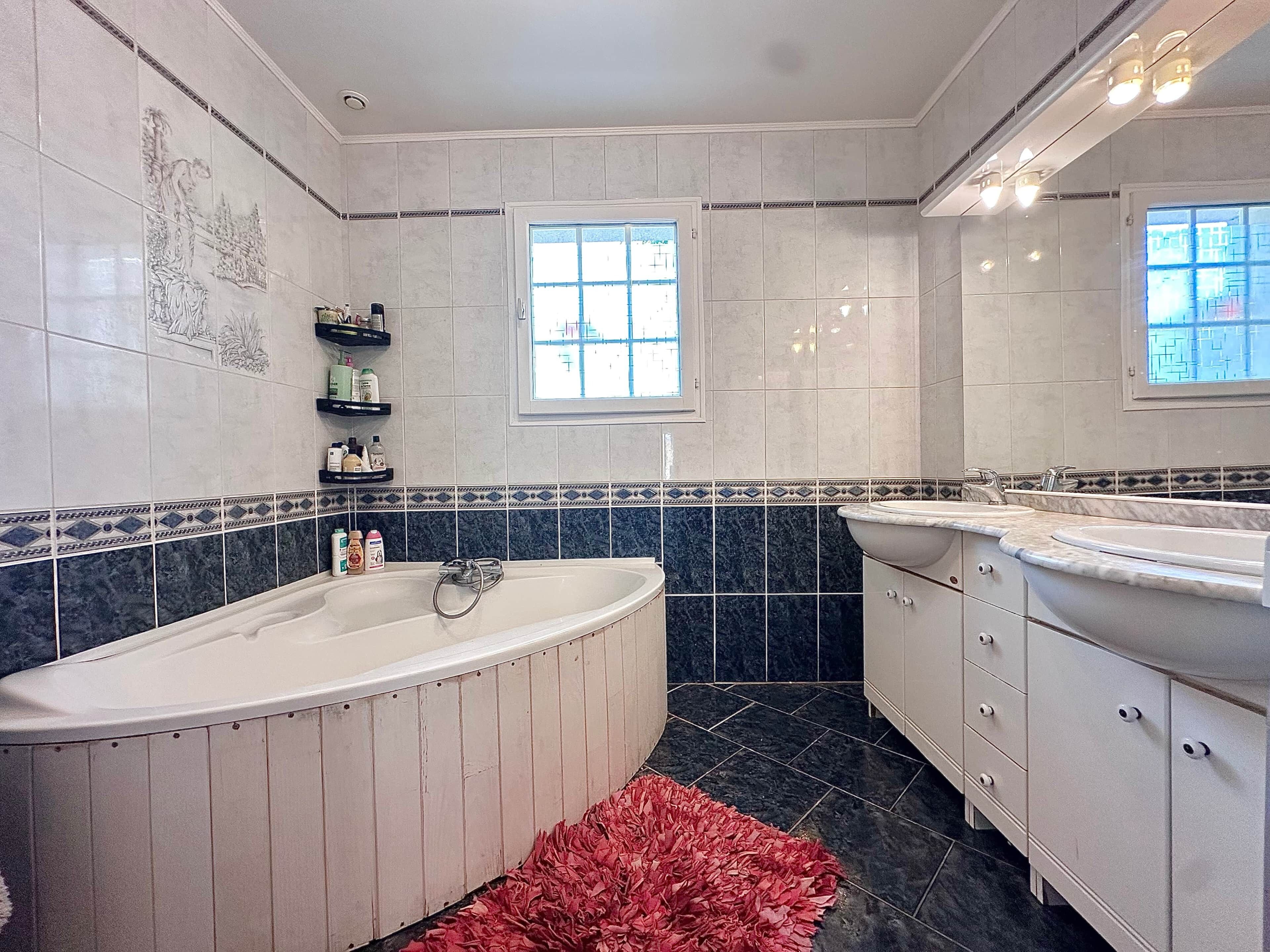 Ein Badezimmer mit einer freistehenden Badewanne, einem Waschtisch und einem Fenster.