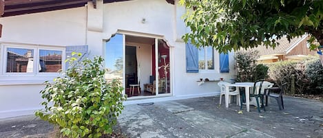 A house with a patio, a dining table with chairs, and a small garden.