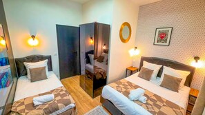 Een hotelkamer met twee bedden, een spiegel, een wand met decoratief patroon en twee bedlampjes.