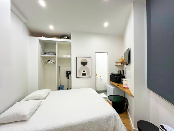 A hotel room with a bed, a wardrobe, a desk with a computer, a chair, and a television. - Urban Flat 165 - Studio Boétie Paris (Paris)