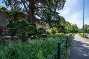 A pathway alongside a building with a heritage sign, bordered by a metal fence and lush greenery. - Luxury stay in Cambridge City Centre – Flat 2 - Pass the Keys (Cambridge)