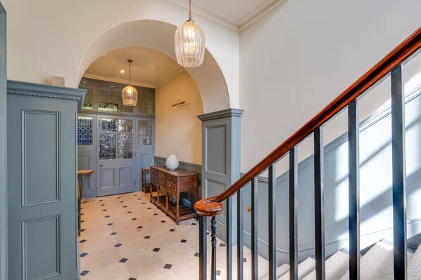 A staircase with a wooden handrail and a patterned floor leading to a room with a door and a window. - Luxury stay in Cambridge City Centre – Flat 2 - Pass the Keys (Cambridge)