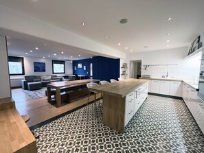 A modern kitchen with a wooden island, white cabinets, and a patterned floor. - UrbanFlat 166 - Luxury Apartment in Center of Paris (París)