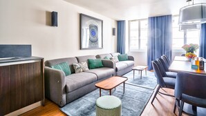 A modern living room with a sofa, coffee table, and dining area. - Ponceau Triple Appartements (París)