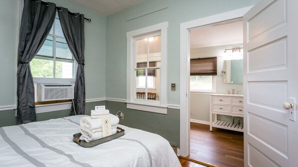A bedroom with a bed, a window with curtains, a bathroom with a sink and mirror, and a door leading to another room. - Exclusive Whole-Inn Lodging: The Ultimate Shenandoah Valley Group Retreat at The Buckhorn (Churchville)