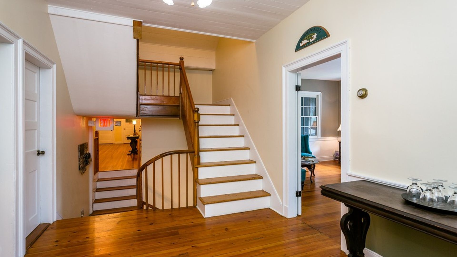 A staircase with wooden steps and a handrail, leading to a room with a door marked 'EXIT'.