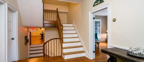 A staircase with wooden steps and a handrail, leading to a room with a door marked 'EXIT'.