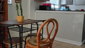 A kitchen with a dining table, chairs, a potted plant, and cabinets.