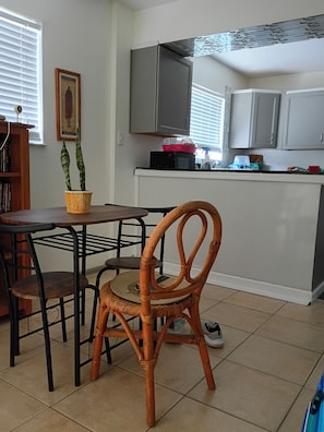 A kitchen with a dining table, chairs, a potted plant, and cabinets.