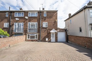 A residential building with a brick facade, multiple windows, and a garage door. - 4-Bedroom Family Home / Parking / Station - Pass the Keys (Belvedere)