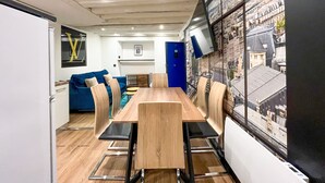 Un comedor moderno con una mesa y sillas de madera, un sofá azul y un mural con vistas a la ciudad.