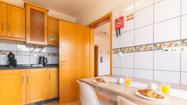 Eine Küche mit Holzausstattung, einer Kaffeemaschine und einem Tisch, gedeckt mit Croissants, Saft und einer Tasse.