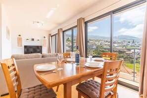 A dining area with a table set for two, a sofa, and a TV in the background. - Porlamar III by Atlantic Holiday (Calheta)