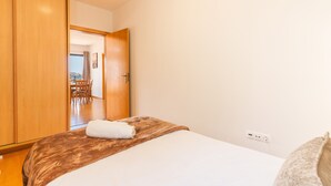 Ein Hotelzimmer mit einem Bett, einem Holzschrank und Blick auf einen Essbereich durch eine offene Tür.