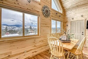 A wooden interior with a dining table, chairs, a clock, and large windows offering a snowy landscape view. - Fantastic 3BR Mountainview Dog Friendly (South Fork)